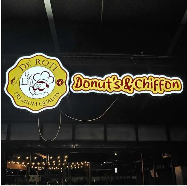 De Roti bakery lit sign under a canopy