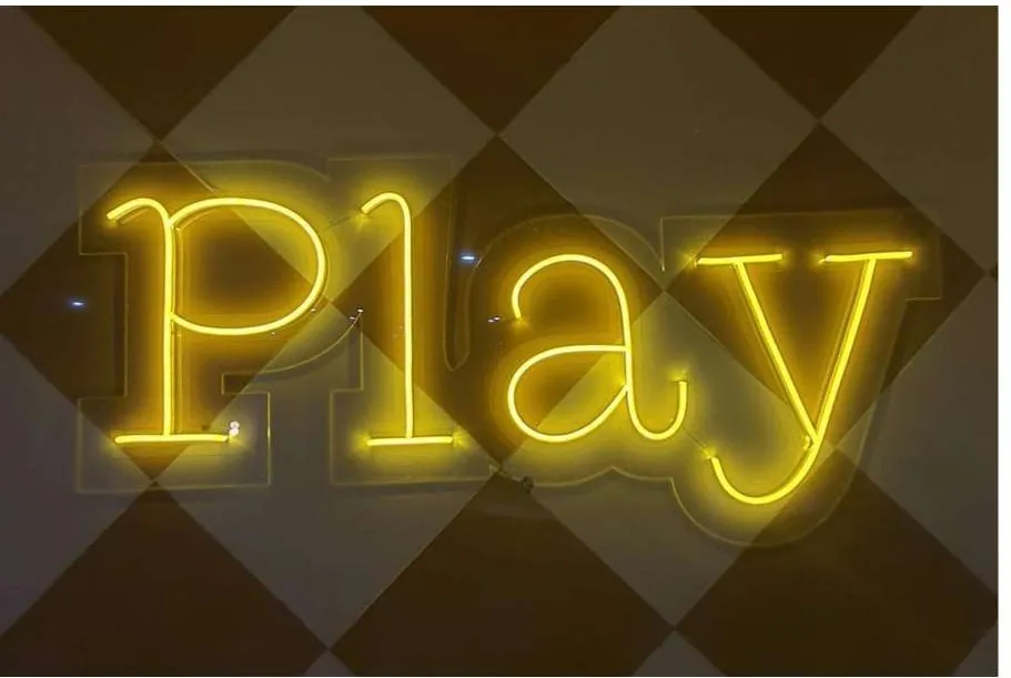Yellow neon word Play on a patterned wall